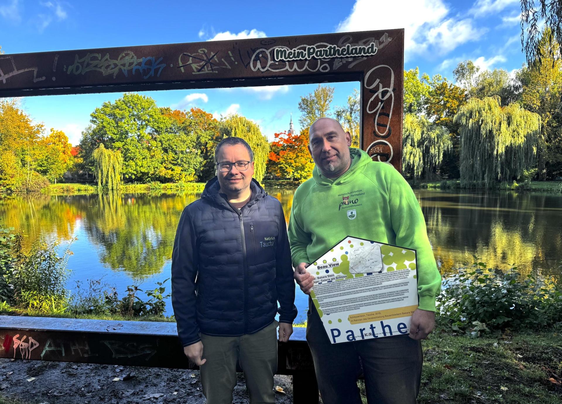 Bürgermeister Tobias Meier und Axel Weinert von der Naturschutzstation (v.l.) am BeauView-Rahmen am Schöppenteich, der seit heute den Zusatz „Mein Partheland” trägt. (Foto: Daniel Große [danielgrosse] (info@taucha-kompakt.de, dg24))