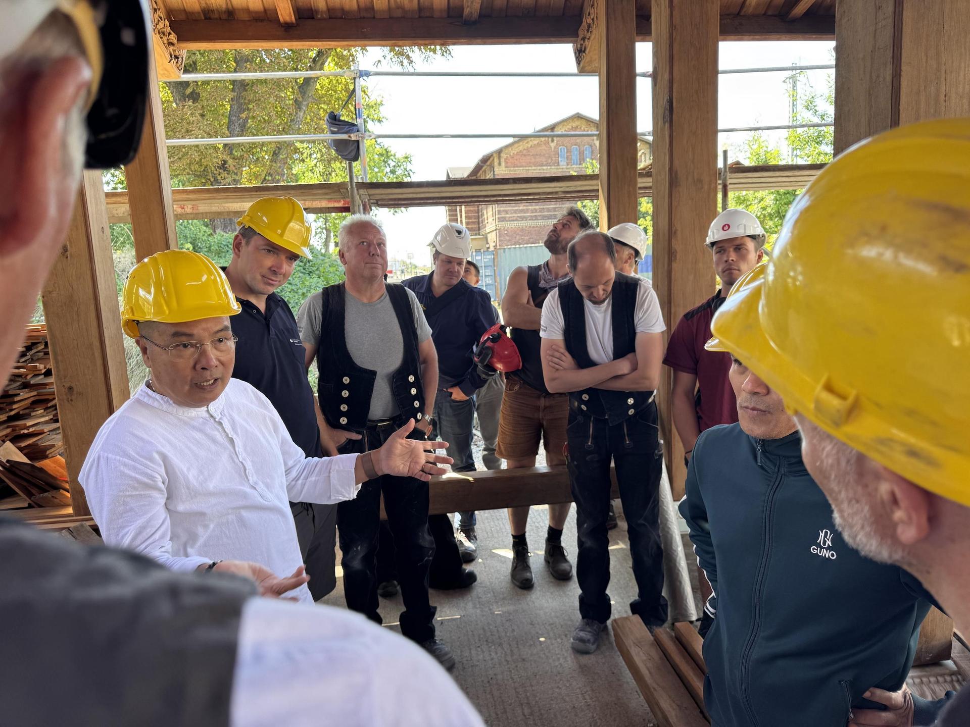 Quang Vinh Dao (links) erklärt den Handwerkern den Bau des Holztempels. (Foto: Daniel Große)