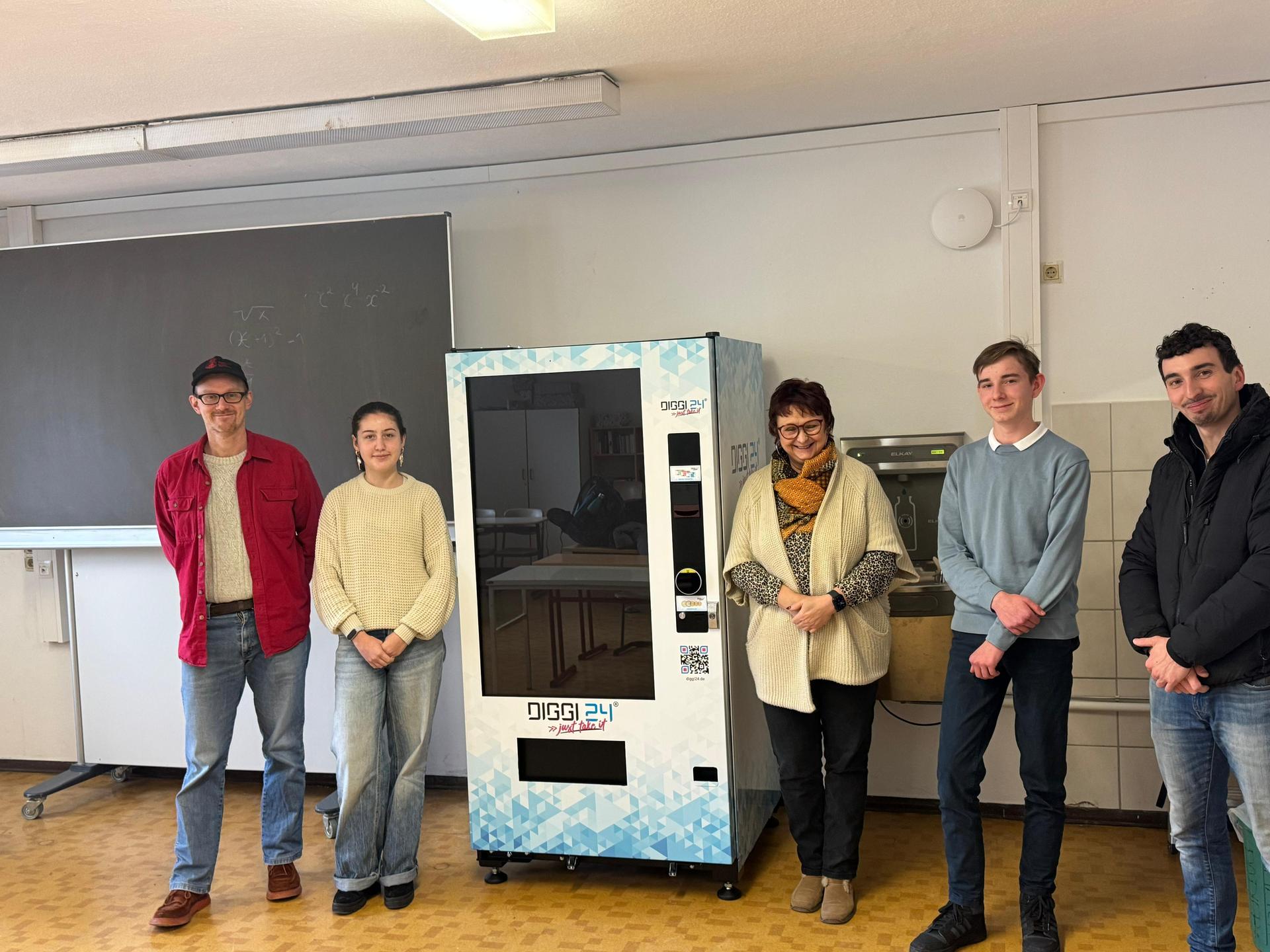 Große Freude bei Schulleiterin Kathrin Rentsch, Marcus Rößner von IMPULS Taucha (links) sowie den Schülervertretern. Benedikt Döll, Leiter für Partnerschaften und Standortentwicklung bei der Diggi24 GmbH (rechts) stellte den Automat auf. (Foto: IMPULS Taucha)