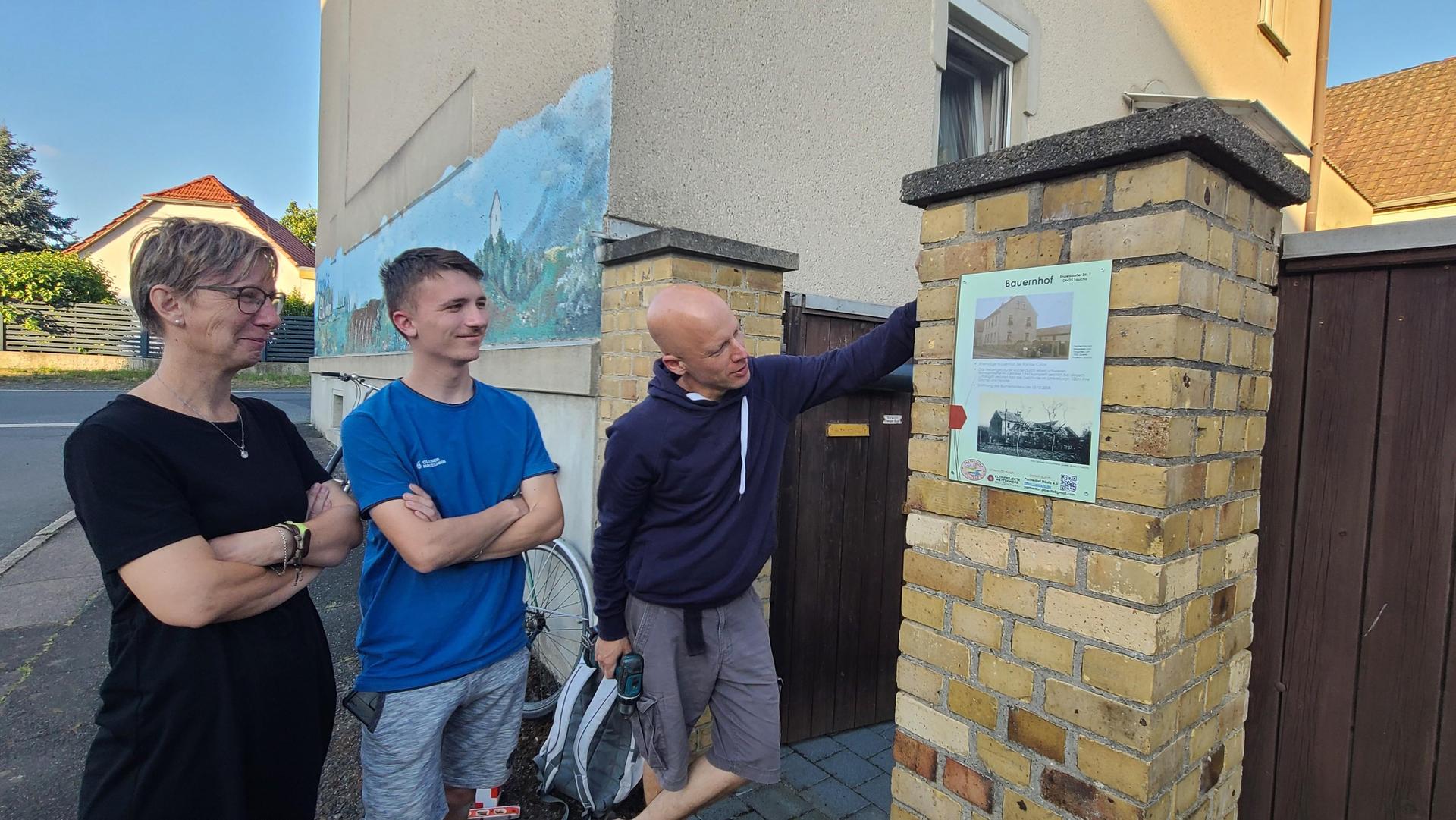 Anwohnerin Conny Bursian und Sohn Tom freuen sich mit Jan Dossin (rechts) über das Schild am Hoftor der Engelsdorfer Straße 1. Es berichtet unter anderem von den Zerstörungen durch einen Bombentreffer im Krieg. (Foto: Heike Liesaus)